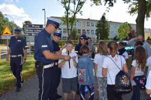 policjanci z uczniami rozdają odblaski