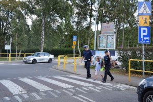 policjanci uczą przechodzić ucznia przez jezdnię