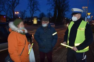 Policjant rozdaje odblaski przechodnią