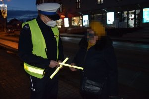 Policjant rozdaje odblaski przechodnią