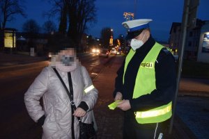 Policjant rozdaje odblaski przechodnią