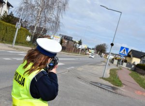 Policjantka ruchu drogowego przeprowadza pomiar prędkości.